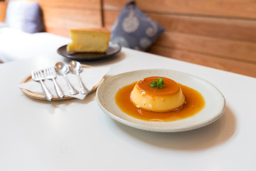 Pudding Caramel Custard (creme caramel) with piece of of vanilla cake on white table