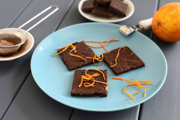 Healthy homemade dark chocolate bars with orange rind on turquoise plate