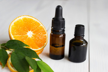 Orange, leaves and brown bottles with essential oil on wooden table
