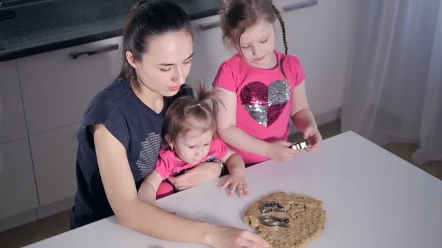The slowmotion shooting of the mother and the girls making cookies. Portrait. Close-up. HD.
