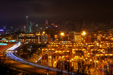 Fototapeta na wymiar Aerial view of the Kwai Tsing Container Terminals in Hong Kong with light trail from vehicles and skyscrapers as background