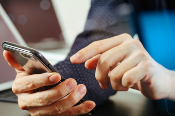 close up of businessman hand working with mobile phone and laptop and digital tablet computer in modern office