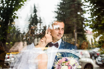 beautiful wedding couple, gentle and romantic kiss behind the glass
