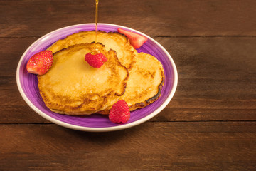 Honey poured over homemade pancakes with fresh fruit