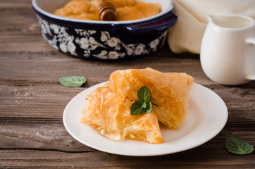 Slice of Homemade baklava stuffed cream with honey sirup on wooden table. Eastern sweets. Ramadan food