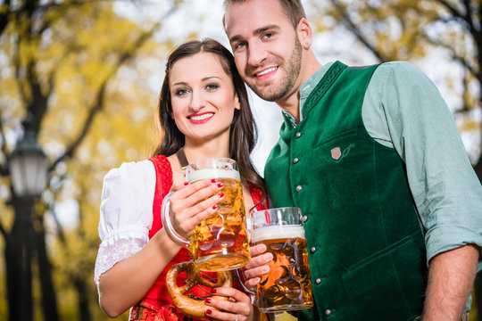 Bayer und Bayerin mit Bierkr&uuml;gen und Bretzeln im Herbst