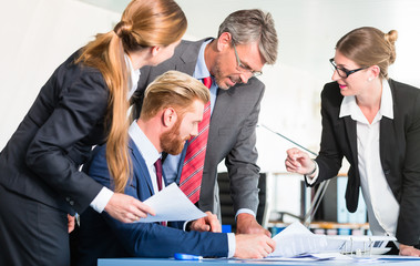 Manager checking documents in front of assistants