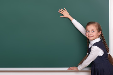 elementary school girl put hands on chalkboard background and show blank space, dressed in classic black suit, group pupil, education concept
