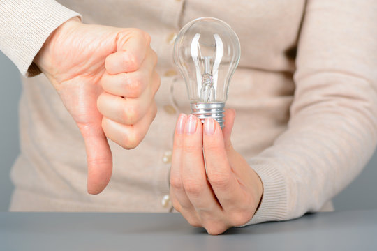 Woman holding light bulb and shows dislike