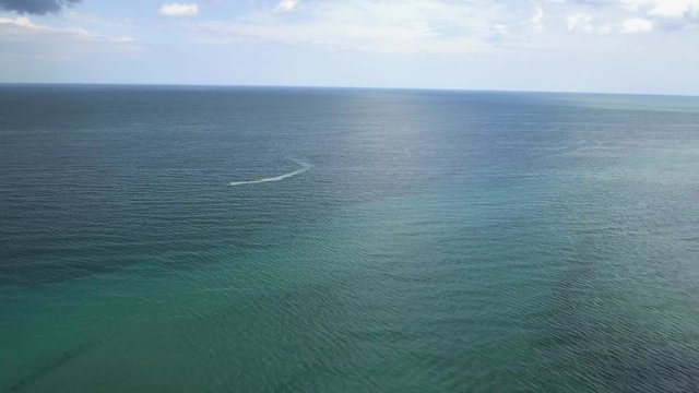 Aerial shot of ocean with jet skis passing by