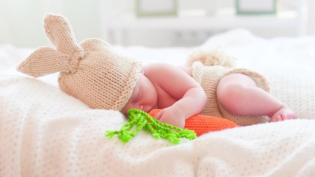 Newborn baby in funny bunny costume sleeping in his bed. 4K UHD video 3840X2160