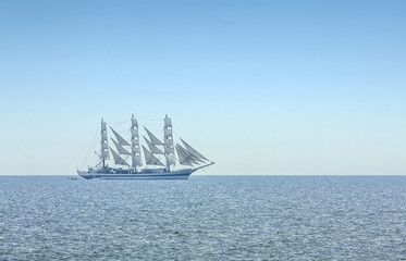 Three masted windjammer in full sails on the Black Sea on the horizon.