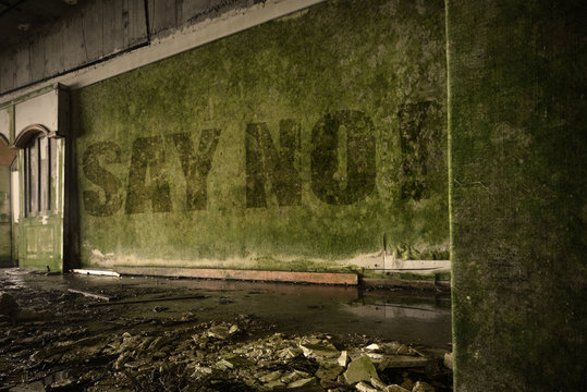 text say no on the dirty wall in an abandoned ruined house