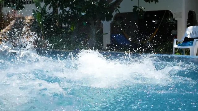 guy playing ball in the pool. sports outdoors. Jump into the pool with splashes