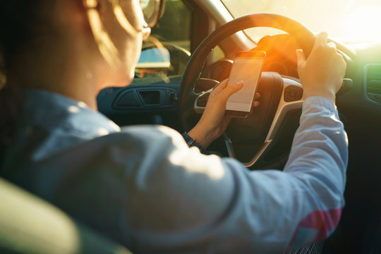 Happy Woman Uses A Navigator In A Smartphone While Driving A Car