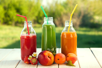 glass of detox smoothie and fruit on wooden table in the garden