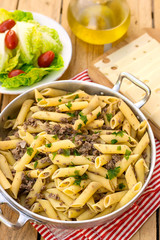 Pasta penne rigate with ground meat and onions in a pan