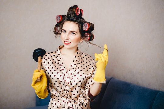 Woman With Curls On The Head Of A Runner In Clothes For Home Is Holding A Cleaner To Clean The Clog In The Pipes Of The Plunger. Concept Clean The Blockage With Their Own Hands.