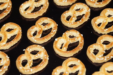 Sweet pretzel sprinkled with sesame seeds isolated on a black background