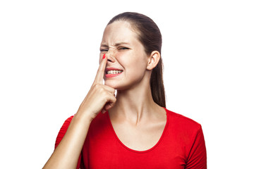 Fototapeta premium Portrait of liar woman in red t-shirt with freckles. looking up and touch her nose, studio shot. isolated on white background.