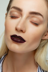 Close-up of beautiful female face, closed eyes, natural make-up and dark red mat lips