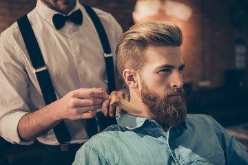 Classy dressed barber shop hairdresser is cleaning client`s neck with a brush and presents his work...