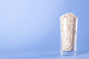 Raw oatmeal in a glass on a blue background