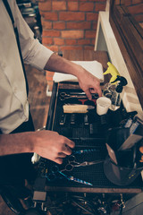 Close up cropped photo of accessories of a barber shop stylist. He is organizing them in the order  at his work place