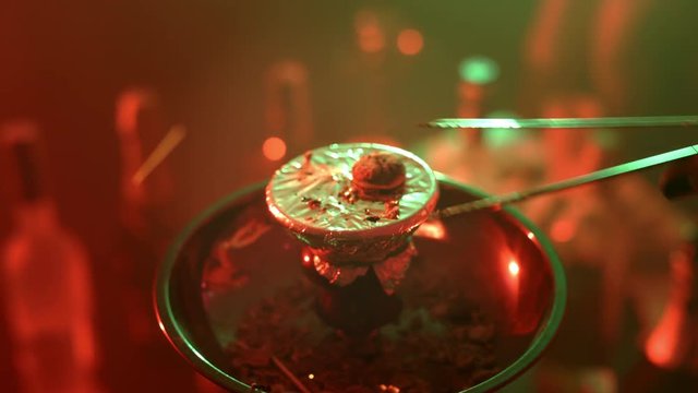 Female hands take hot charcoal with metal tweezers for hookah. Close up hand put hot coal on bowl of nargile. Coal for hookah smoking is placed on bowl with a falcon. Hot coal for shisha smoking