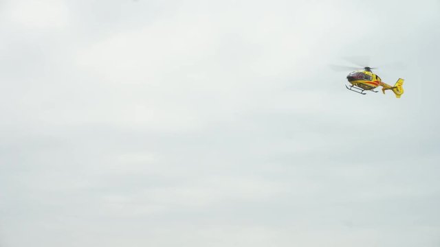 Lublin, Poland - Nowember 2016: Yellow helicopter taking off against a grey sky. Long shot.