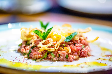 Beef tartare with fried onion lies on the plate.
