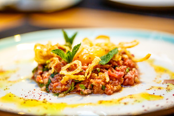 Beef tartare with fried onion lies on the plate.
