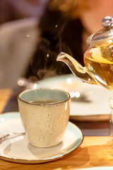 Hot tea is poured into the Cup from the glass teapot