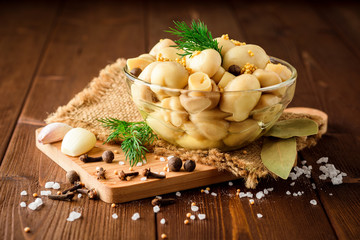 Fototapeta na wymiar Pickled mushrooms in glass bowl with spices and dill on wooden table.