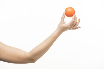 The hand holds an orange round object