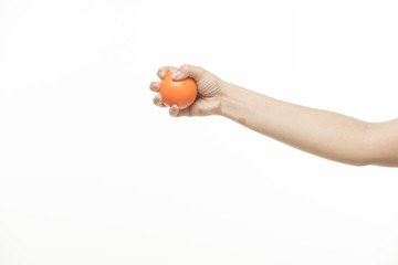 The hand holds an orange round object