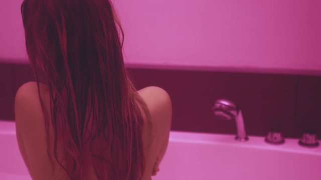 Sexy woman in bathroom. Naked back of naked girl. Girl nude body with long hair takes bath. Girl with beautiful body. Close up of sexy lady with bare back taking bath