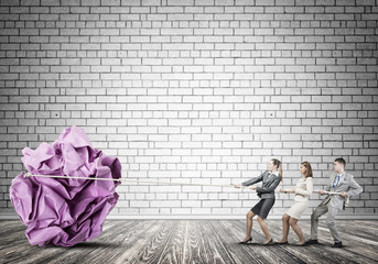 Young business people and huge paper ball as symbol of creativity