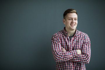 Portrait of handsome young man in casual shirt keeping arms crossed and smiling while standing...