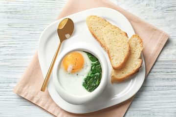 Plate with tasty egg and spinach on wooden table