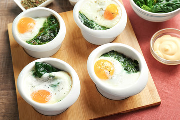 Bowls with tasty eggs and spinach, closeup