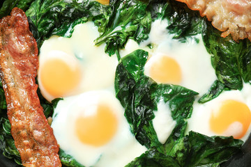 Frying pan with tasty eggs, spinach and bacon, closeup