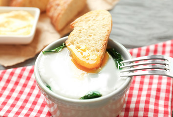Bowl with tasty egg and spinach on wooden table