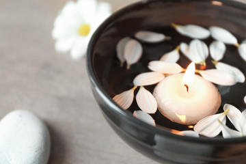 Fototapeta na wymiar Beautiful spa composition with flower petals on water and candle, closeup