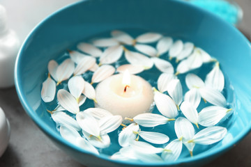 Beautiful spa composition with flower petals on water and candle, closeup