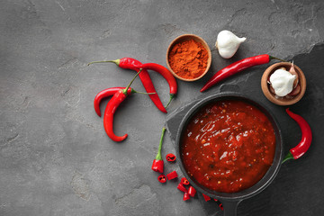 Composition with tasty chili sauce on grey textured table