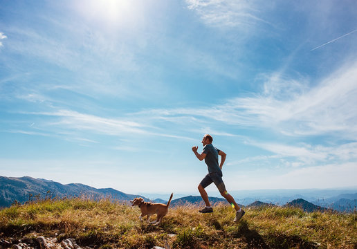Man runs with his beagle dog on mountain top