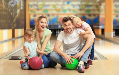 Happy family sitting on floor in bowling club