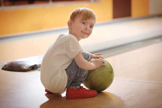 Cute child with ball in bowling club