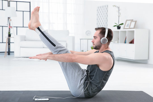 Man doing yoga and listening to the music at home